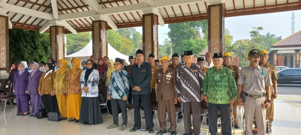 Foto bersama peserta kegiatan mengenakan batik, pakaian organisasi, dan seragam di area terbuka.